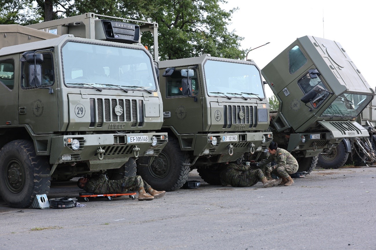 Logistics personnel conducting maintenance tasks on tactical transport vehicles